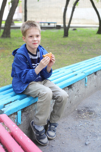 男孩在公园里吃汉堡包