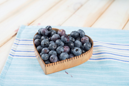 在心脏形状篮子里的厨房桌子上的新鲜蓝莓