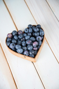 在心脏形状篮子里的厨房桌子上的新鲜蓝莓