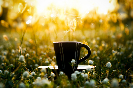 每天早上喝咖啡与花卉草背景中的黑色茶杯