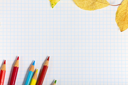 笔记本用彩色的铅笔和秋天的落叶