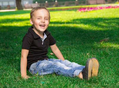 微笑的小男孩，坐在草地上
