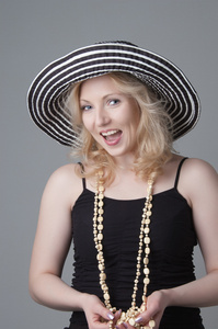年轻漂亮的笑金发的女人，一顶帽子和一件黑色的连衣裙