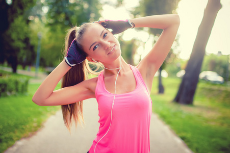 运动女孩工作和伸展在公园里一边听音乐，健身概念的肖像