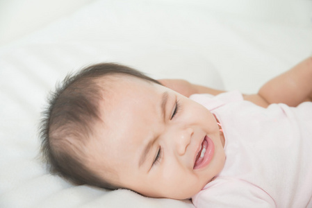 亚洲的可爱的小女孩婴儿在床上哭泣