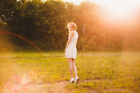 在公园里那天阳光明媚的白色连衣裙的女孩