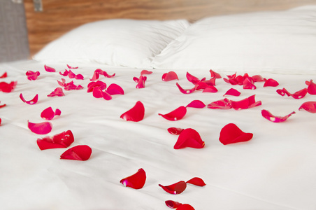 玫瑰花瓣洒在白色的床上用品