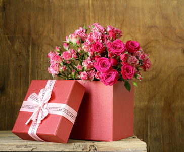 束玫瑰花与礼品盒，木制的背景上