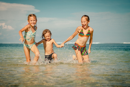 三个快乐的孩子在一天时间在沙滩上玩