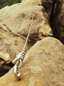 详细的薄薄的铁绳端锚定登山者进入砂岩岩石。铁扭绳固定用螺杆夹块中。岩石之间的安全行人路