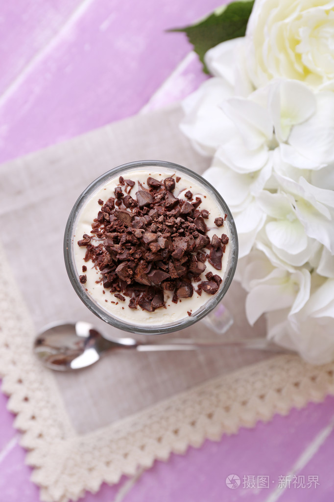 酸奶奶油夹心巧克力切碎的巧克力和牛奶什锦早餐服务在玻璃上彩色木