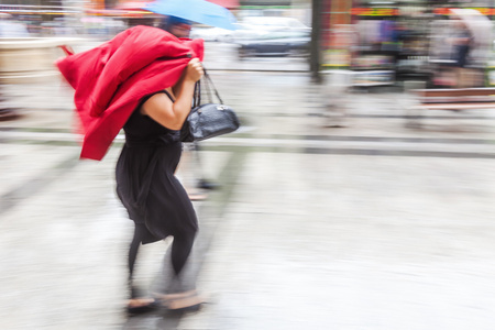 保护她的头一件夹克，走在多雨的城市与女人的图片