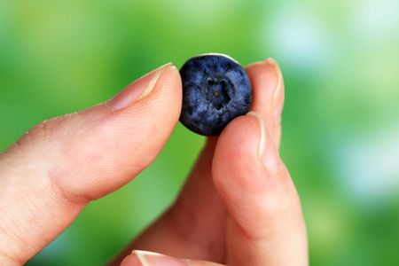美味的成熟蓝莓对自然背景的女性手
