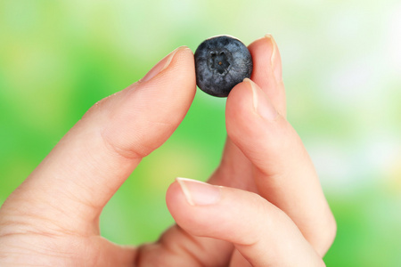 美味的成熟蓝莓对自然背景的女性手