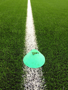 亮绿色蓝色塑料锥上画的白线。与核心的磨黑橡胶塑料足球绿色草坪操场