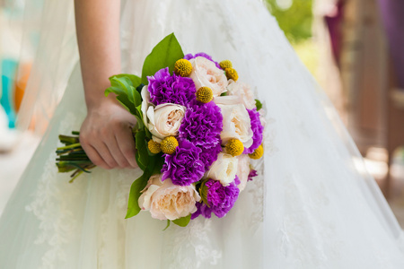 婚礼礼服反对束康乃馨的新娘举行紫
