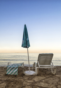 sedie e ombrellone sula spiaggia allalba