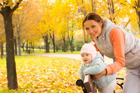 年轻的母亲和她的孩子在公园秋天