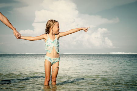 小女孩站在沙滩上，在白天的时间