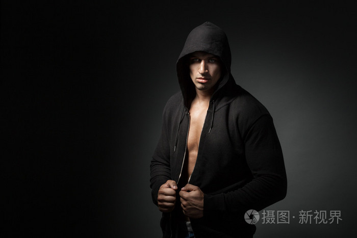强壮的男人,穿着连帽衫上黑色的背景,副本孤立