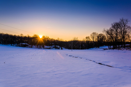 在冰雪覆盖的农田，在农村纽约县，宾夕法尼亚的落日
