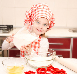 把面粉烘焙饼干的厨师帽带微笑的小女孩