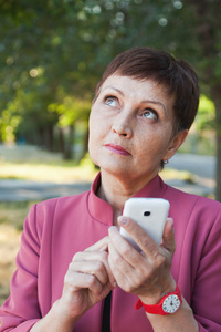 沉思的有吸引力的女人与手中的移动电话的 50 年