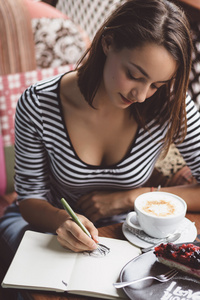 女孩在画一杯咖啡在笔记本中