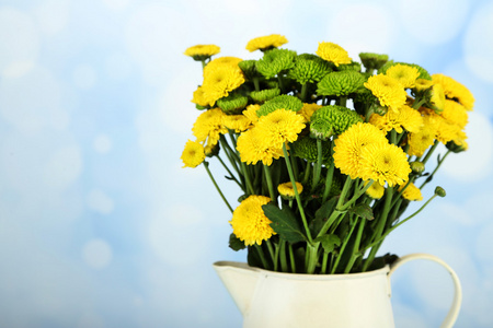 黄色和绿色的花，插在花瓶里在明亮的背景上
