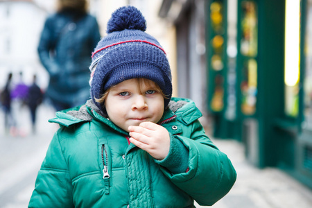 蹒跚学步的小男孩步行穿过城市，在寒冷的肖像