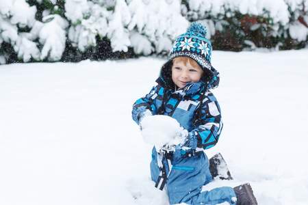 可爱的小孩男孩在冬季一天玩雪