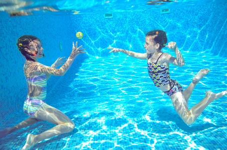 快乐积极的孩子在游泳池里游泳和玩水下