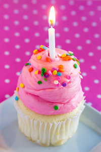 粉红色糖霜和蜡烛的香草蛋糕