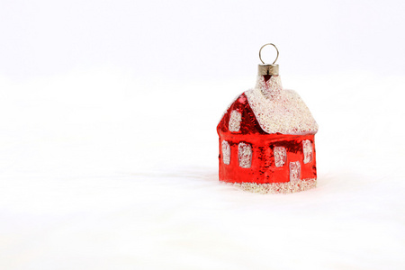 红色光泽的圣诞装饰   站在白色的皮毛背景上的小房子