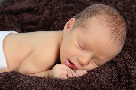 刚出生的婴儿睡在棕色的毯子上
