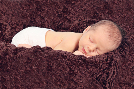 刚出生的婴儿睡在棕色的毯子上