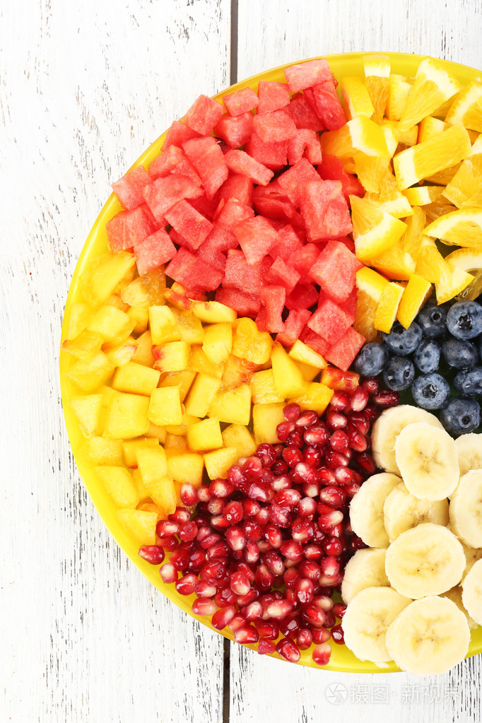 在木制的桌子上的盘子切水果