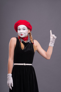 用红色帽子和白脸做鬼脸无线女 mime 的肖像