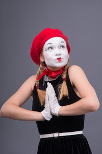 用红色帽子和白脸做鬼脸无线女 mime 的肖像