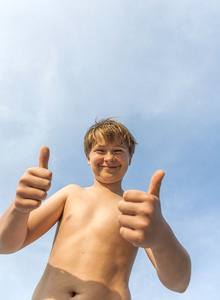 快乐微笑的年轻男孩竖起大拇指 fingersign