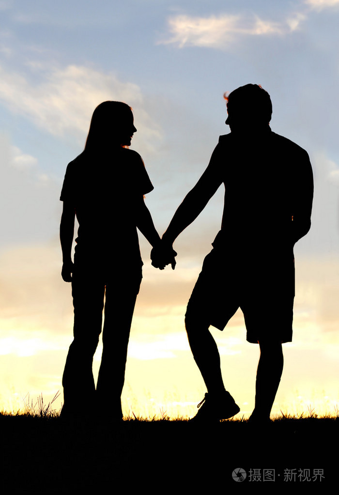 幸福的夫妇手拉手走上在日落时的剪影