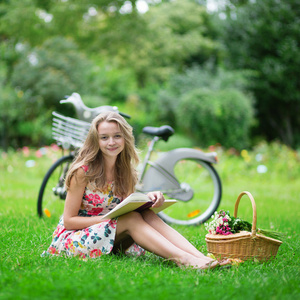 年轻漂亮的女孩在公园看书