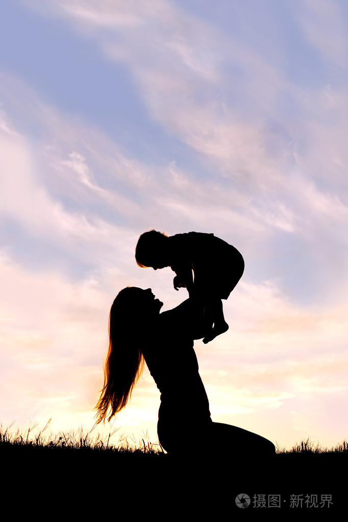 幸福的母亲抱着婴儿在外面玩的剪影