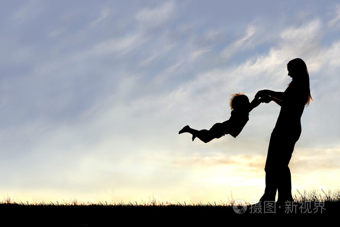 在日落时玩外面的孩子的母亲的剪影