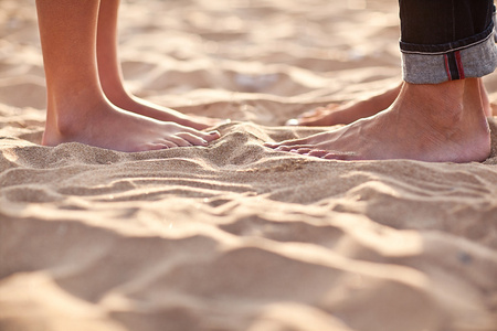 夫妇的腿在沙滩上