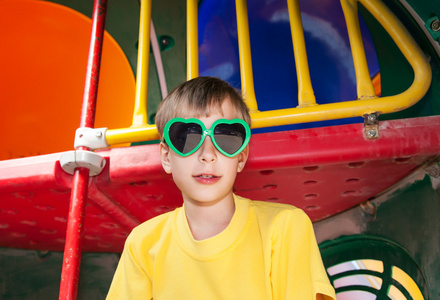 美丽的孩子穿着滑稽的太阳镜在夏天在操场上玩