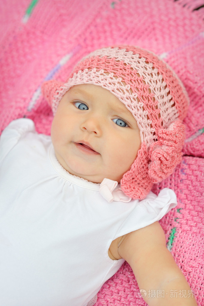 一个可爱的小宝贝女孩仰望,粉红色的毯子上
