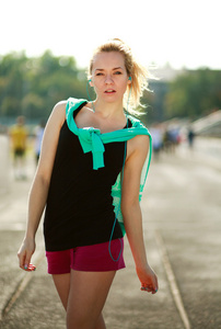 年轻的运动型女人戴着耳机跑步机上午
