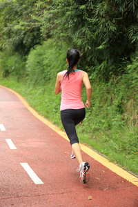 年轻的健身女人在森林步道运行