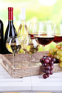 酒瓶和酒和成熟的葡萄，对自然背景下桌上的杯子